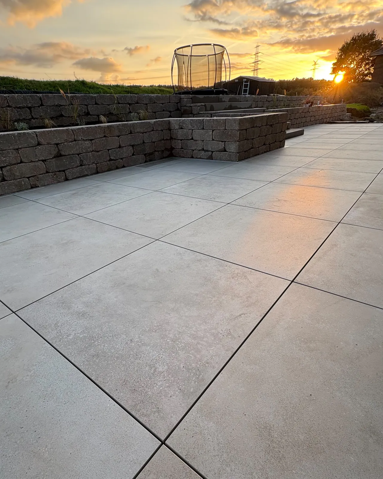 Helle Terrassenplatten mit Mauer im Abendlicht